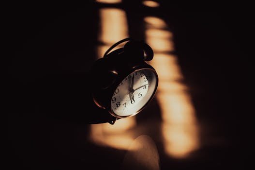 A retro analog alarm clock in moody shadows and warm lighting.
